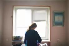 ქალი ფანჯრის წინ, აუთოვებს