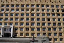 მოხუცი ქალი ჯოხით დგას საქართველოს მთავრობის შენობის წინ