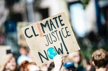 people gathered outside buildings holding Climate Justice Now signage