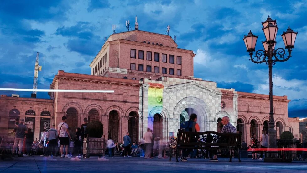 An evening scene featuring people in front of an illuminated building in the Armenian capital, Yerevan.